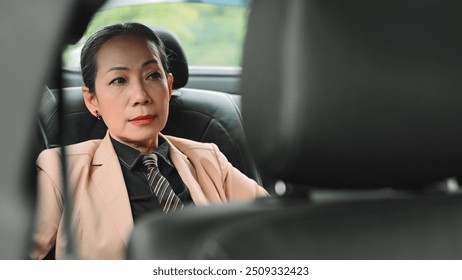 A seasoned professional woman sits thoughtfully in the backseat of a car, gazing out the window, contemplating the next steps in her business strategy, Reflective Moments with A Quiet Ride. - Powered by Shutterstock