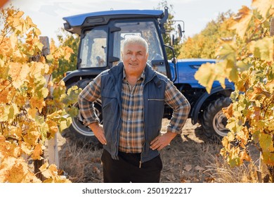 A seasoned winemaker, framed by the stunning backdrop of an autumn vineyard, stands confidently near a tractor, capturing the essence of winemaking expertise in this picturesque setting. - Powered by Shutterstock