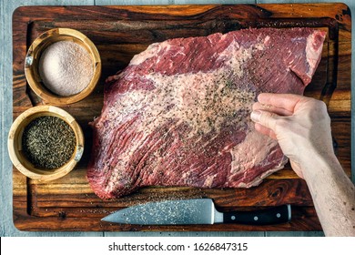 Seasoning a beef brisket with salt and pepper before barbequing on a smoker