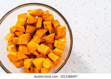 Seasoning Cubed Sweet Potatoes To Make Oven-roasted Sweet Potatoes.