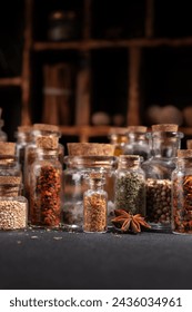 Seasoning (herbs and spices) in small bottles with cork on a dark background