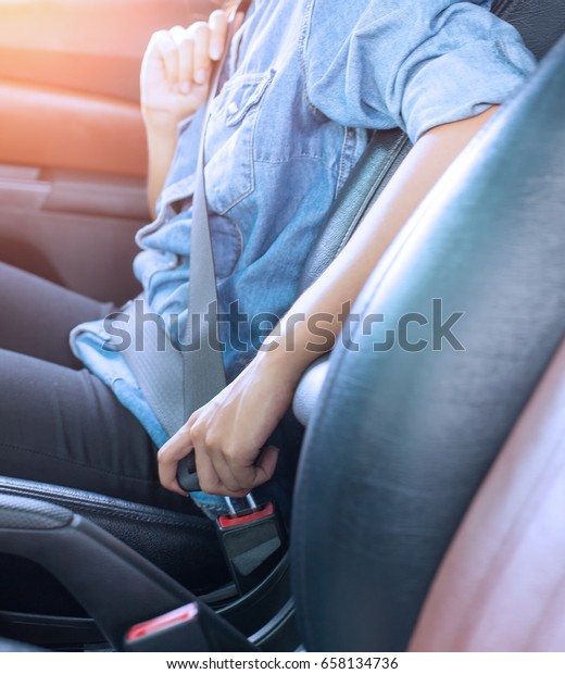 seat\
belt: woman hand fastening a seat belt in the\
car