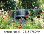 Seat and table in a garden surrounded by flower beds full of heleniums and dahlias in late summer