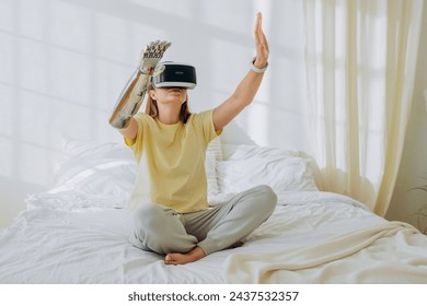 Seated comfortably on her bed, a young woman with a robotic arm explores virtual worlds wearing a VR headset, blending technology with daily life.Exploring Virtual Reality at Home - Powered by Shutterstock