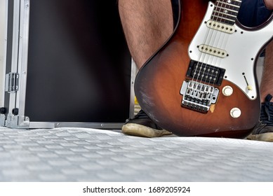 Seated Man Holding Guitar Between His Legs With Hard Case Beside