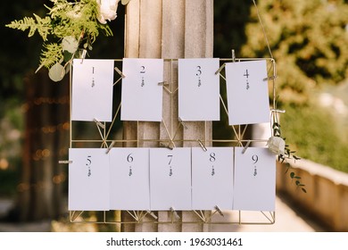 Seating plan. Numbered blank cards on a metal wicker stand hang on a column. Inscription: 1, 2, 3, 4, 5, 6, 7, 8, 9