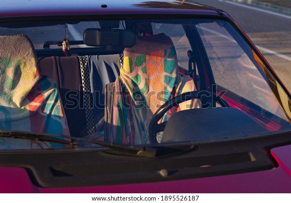 The seats of a red vintage car covered in\
colorful towels (Marche, Italy,\
Europe)