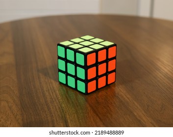 Seattle - Aug8 2022: Solved Rubik Cube. Rubix Cube. Rubik's Cube. Puzzle, Green, Yellow Orange Sides On Wood Wooden Table Background. Isolated Perspective. Solution To Problem Solving.