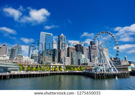 Seattle Ferris wheel, skyline and waterfront in sunny day with blue sky and clouds. The great wheel in Seattle downtown.