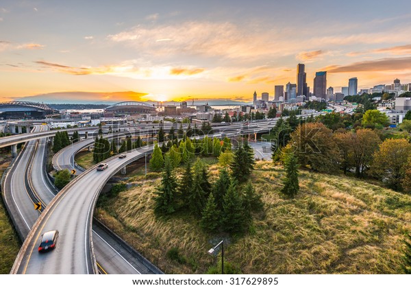 シアトルの高層ビル群とインターステートの高速道路は 夕暮れの時間 米国ワシントン州シアトルのエリオット湾と水辺の背景に集まっています の写真素材 今すぐ編集