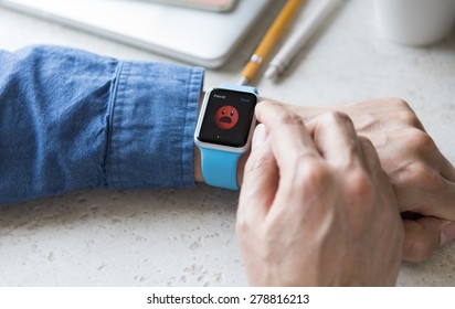 SEATTLE, USA - May 17, 2015: Man Wearing Sport Apple Watch With Blue Rubber Band. Upset Face Emoji Displayed.