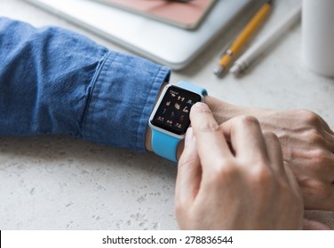 SEATTLE, USA - May 17, 2015: Man Wearing Sport Apple Watch with Blue Rubber Band. Emoji Collection Displayed.