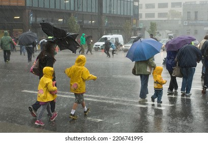 Seattle, WA - 8-6-2018: Young Woman (mother) With Two Children In Yellow Raincoats During A Heavy Rain And Wind Storm.  Umbrella Is Blown Inside Out. Soft Focus Emphasized Severity Of Storm