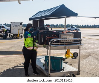 Seattle, WA, USA 7 23 2021 An Airport Female Worker In A Mask Is Putting On The Cart The The Carry-on Luggage That Doesn't Fit In The Air Cabin