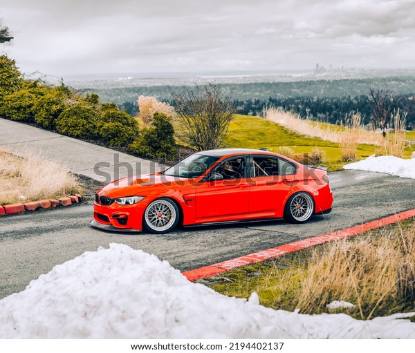 Seattle, WA, USA\
August 21, 2022\
Red BMW M3\
parked showing the front drivers side of the car with trees in the\
background