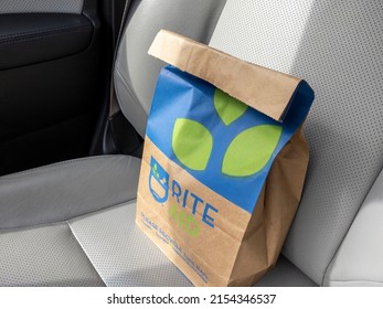 Seattle, WA USA - circa March 2022: Angled view of a brown paper Rite Aid bag sitting inside a car, with a prescription inside.