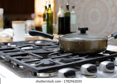 Seattle, WA, USA, July 22, 2020: Dirty Stainless Steel Gas Burner Stove Top With Frying Pan And Vinegar And Oil Bottles And Condiments In The Background