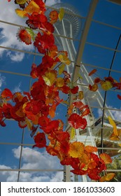 Seattle, WA, USA-October 2012; Close Up Of The Ceiling Of A Greenhouse Exhibition Filled With Bright Orange Glass Sculptures Of Dale Chihuly With The Space Needle Seen Through The Glass