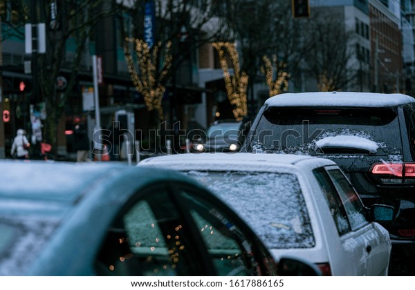 SEATTLE, WASHINGTON -\
JANUARY 15 2020: Seattle Belltown and South Lake Union are covered\
in snow in a rare snow storm. Cars covered in snow. Overcast sky.\
Dark outdoors shots. 