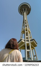 SEATTLE, WASHINGTON STATE, USA - JUNE 2018:  Female Visitor Looking Up At The Space Needle In Seattle Against A Blue Sky.