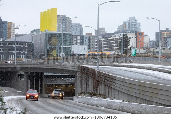 Seattle,\
Washington / USA - February 4 2019: Car exiting the new State Route\
99 Tunnel under downtown Seattle, with ventilation building in the\
background, during a snowstorm on opening\
day
