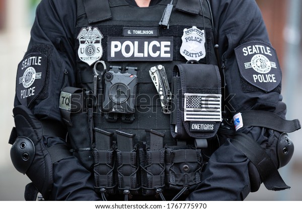 Seattle,\
Washington / USA - July 1 2020: Axon body camera faceless Seattle\
Police Detective standing with a riot\
stick