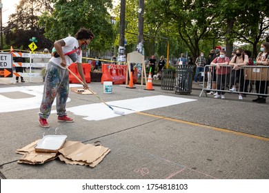 Seattle, Washington / USA - June 10 2020: Activist painting Black Lives Matter sign on Pine Street in the Capitol Hill Autonomous Zone (CHAZ)
