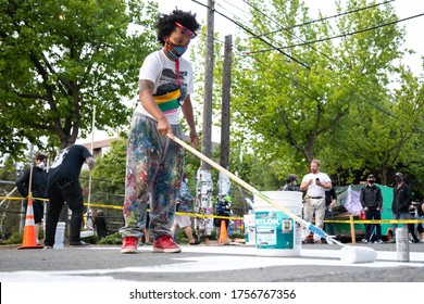Seattle, Washington / USA - June 10 2020:  Wide angle portrait of an artist painting a "Blacks Lives Matter" mural on Pine East Street in the Capitol Hill Occupied Protest (CHOP)