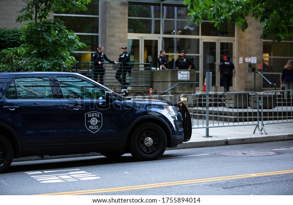 Seattle, Washington / USA - June 10 2020:\
Squad car pared in front of the Seattle Police Department West\
Precinct, with officers standing in the\
background