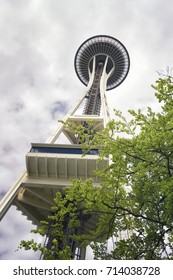 SEATTLE, WASHINGTON, USA - MAY 2, 2017: The Famous Space Needle Tower In Seattle From Below With A Cloudy White Background And Green Trees.