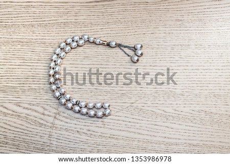 Sebha/bearish of white beats in a shape of crescent on aok wooden background