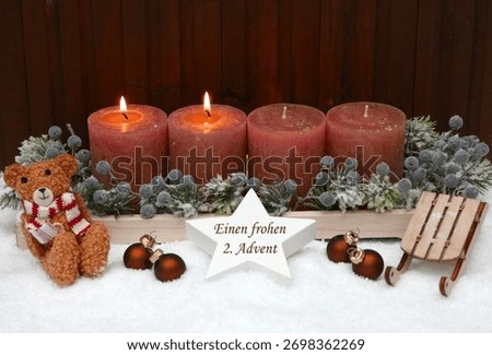 Second Advent: Rust-colored Advent candles decorated with a teddy bear, Christmas baubles, and a sled in the snow. A star bears the inscription 