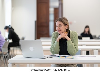 Second Higher Education. Happy Middle-aged Woman Adult Learner Watching Educational Webinar Via Laptop, Sitting At Library Desk, Studying In University As Mature Student, Enjoying Studying For Degree