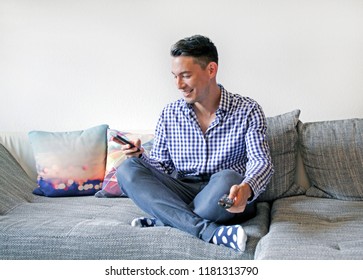 Second Screen - Smiling Man With Remote Control And Smartphone