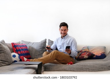 Second Screen - Smiling Man With Remote Control And Smartphone