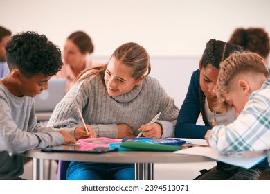 Secondary Or High School Students Collaborating In Study Area With Teachers In Background - Powered by Shutterstock