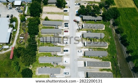 Secondary thoroughfare splits rows of prefab residential structures near municipal boundary lines. Aerial angle captures distinct parking patterns anchoring development in New Braunfels, TX. USA