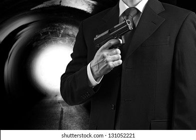 A Secret Agent Holding A Gun Against A Tunnel Background With A Bright Light.