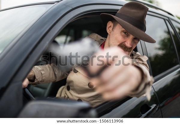 Secret agent using\
gun while driving his\
car