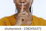 Secret, finger to lips and black woman in studio for privacy, confidential information and face on white background. Mouth zoom, quiet and silence gesture with emoji, gossip or whisper with news