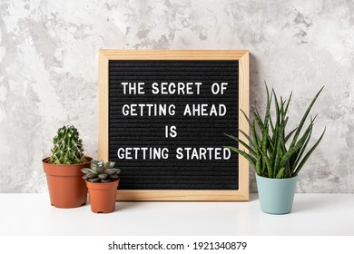 The Secret Of Getting Ahead Is Getting Started. Motivational quote on letter board, cactus, succulent flower on white table. Concept inspirational quote of the day. Front view.