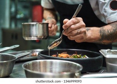 Secret recipe. Close up photo of chef hands with several tattoos adding a sauce to italian pasta Carbonara. - Powered by Shutterstock