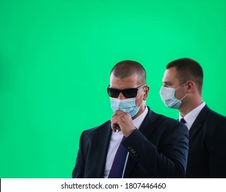 Secret Service Agent Talks Into His Microphone Isolated On Green. Portrait Of Bodyguard Team With Earphone And Black Eyeglasses And Business Suit