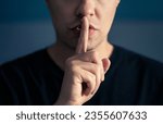 Secret and silence. Quiet silent shh gesture with finger on lips. Man doing expression with hand on mouth. Taboo topic, censorship or freedom or speech. Conspiracy theory. Confidential talk.