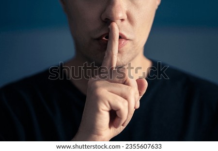 Secret and silence. Quiet silent shh gesture with finger on lips. Man doing expression with hand on mouth. Taboo topic, censorship or freedom or speech. Conspiracy theory. Confidential talk.