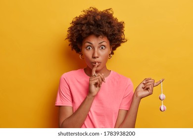 Secret Woman With Curly Hair Holds Kegel Balls For Strengthening Muscles Of Vagina, Keeps Index Finger On Lips, Tells Private Information, Gives Secret Of Receiving Pleasure. Female With Geisha Balls