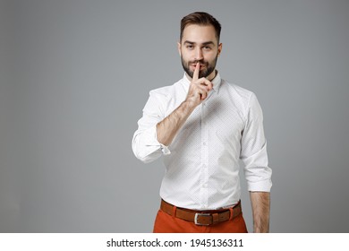 Secret young bearded business man 20s in classic white shirt saying hush be quiet with finger on lips shhh gesture isolated on grey color background studio portrait. Achievement career wealth concept