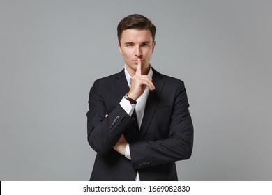 Secret Young Business Man In Classic Suit Shirt Posing Isolated On Grey Background. Achievement Career Wealth Business Concept. Mock Up Copy Space. Say Hush Be Quiet With Finger On Lips Shhh Gesture