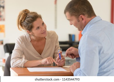 Secretary Helping Male Customer To Complete Paperwork