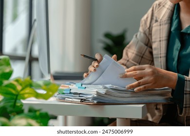 a secretary is organizing stack of paperwork for keep her desk clean, tidy up all finance document on desk because its so messy, a employee archive paper report for neat - Powered by Shutterstock